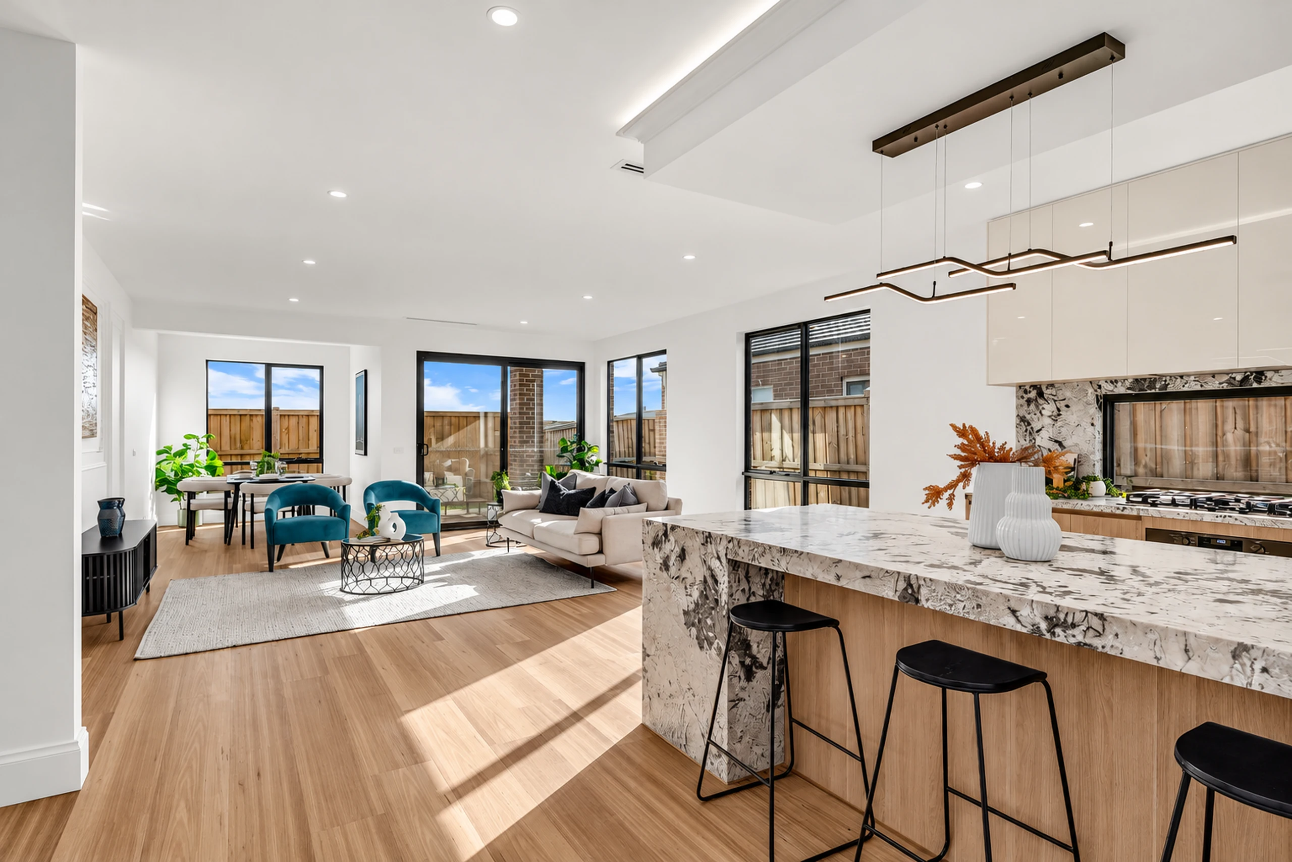 Open-plan living space with oak cabinetry, a stone kitchen island and natural light
